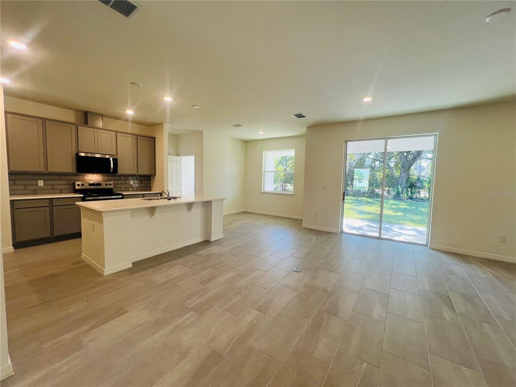 An open-concept kitchen and living area features gray cabinets, a white island, and tile flooring — 4 LYNBROOK DRIVE, PALM COAST, FL