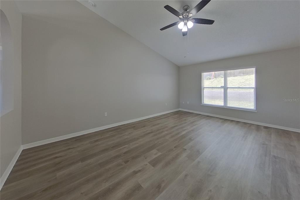 An empty room with light gray walls, wood-look flooring, and a ceiling fan — 921 JAYHIL DRIVE, MINNEOLA, FL