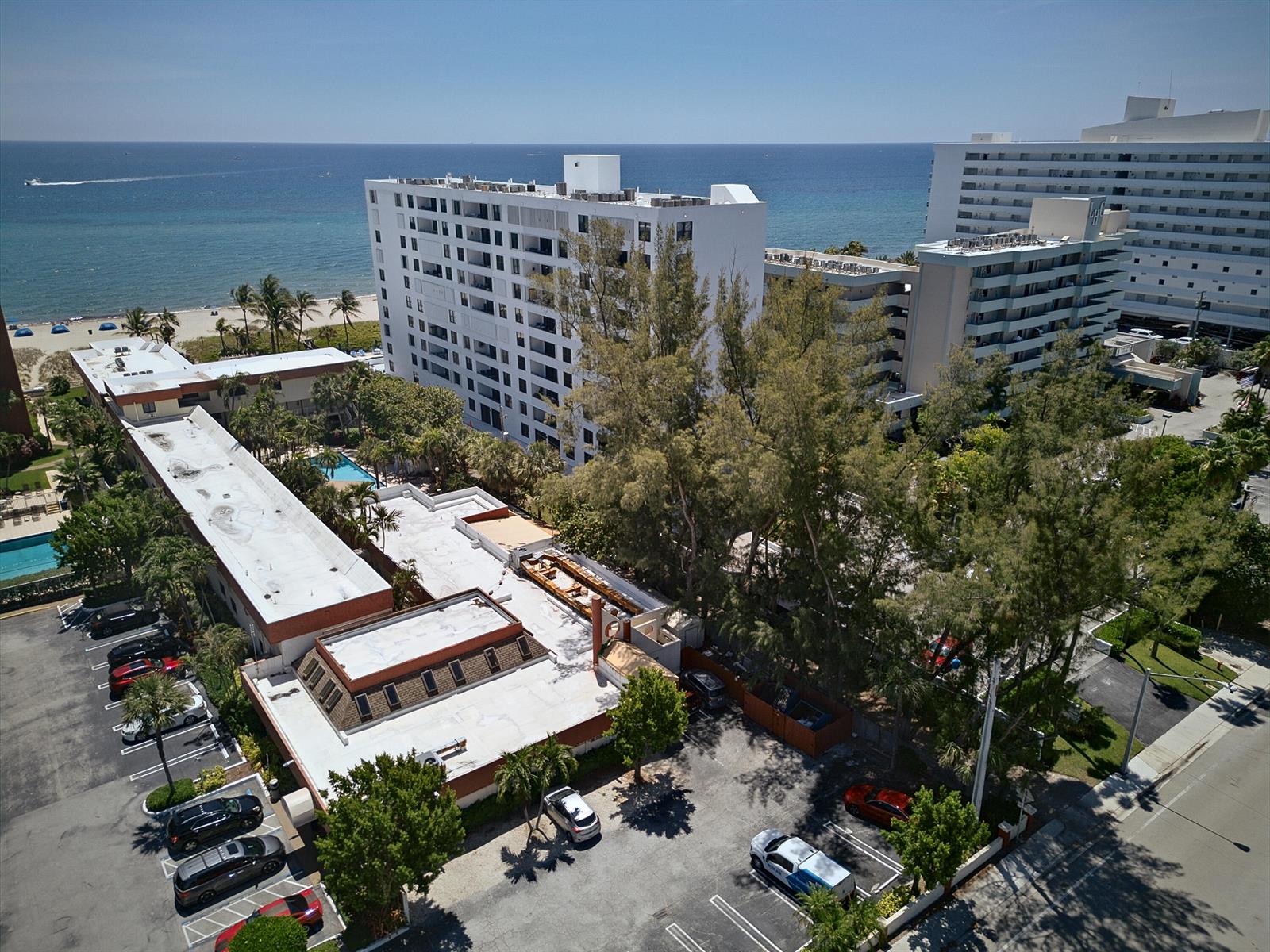 An aerial view shows a multi-story hotel complex with a parking lot near the beach — 1500 N Ocean Boulevard # 803, Pompano Beach FL 33062, POMPANO BEACH, FL