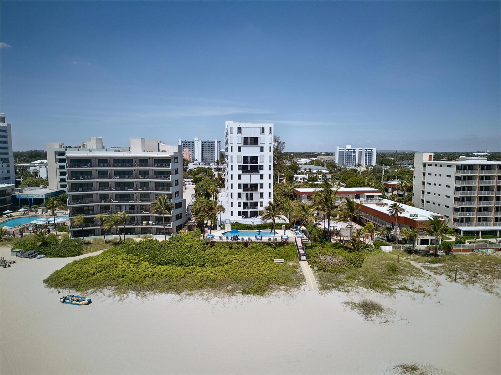 An aerial view of beachfront apartment buildings with swimming pools and surrounding tropical landscaping — 1500 N Ocean Boulevard # 803, Pompano Beach FL 33062, POMPANO BEACH, FL