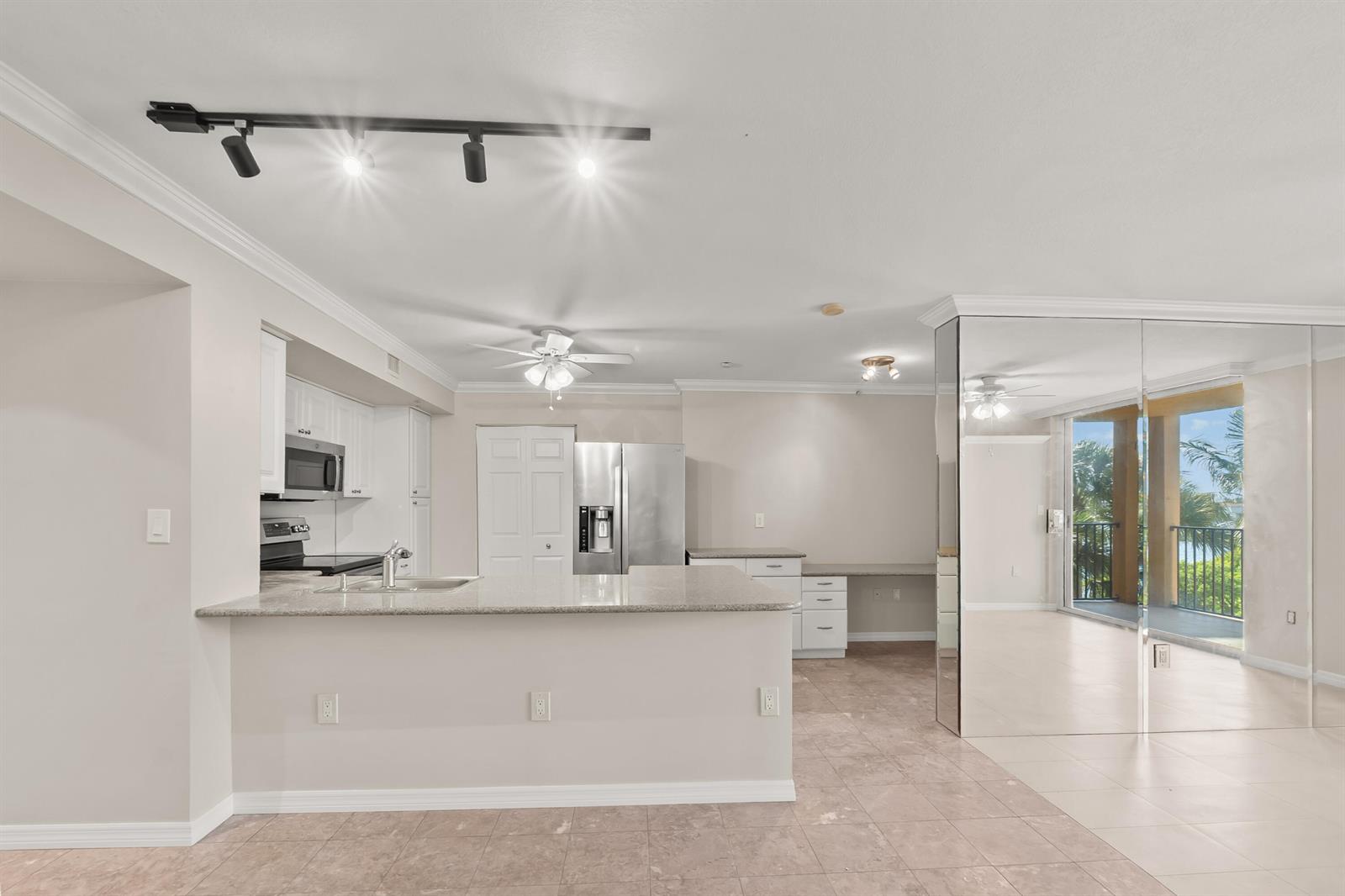 A kitchen with granite countertops and stainless steel appliances opens to a mirrored living area — 1200 Scotia Drive # 403, Hypoluxo FL 33462, HYPOLUXO, FL