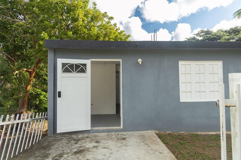 A gray exterior wall features an open doorway, a white door, and a louvered window — 63 SECTOR VILLA BORINQUEN, VIEQUES, PR
