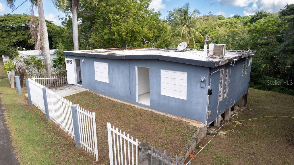 An elevated blue house with a flat roof sits on a grassy, sloped lot — 63 SECTOR VILLA BORINQUEN, VIEQUES, PR