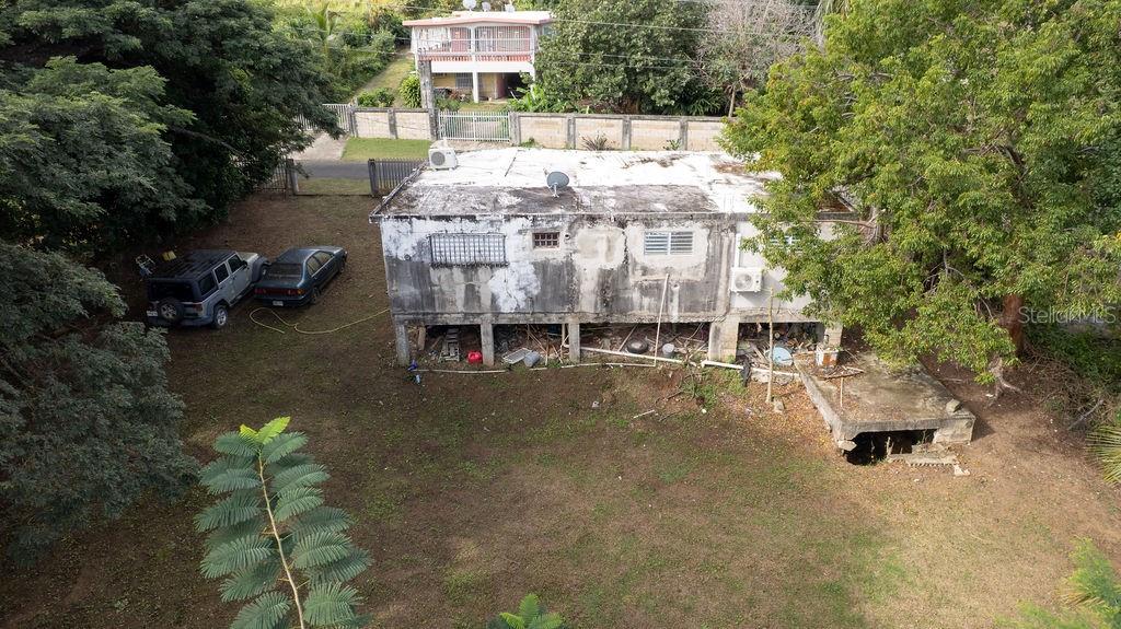 An elevated, weathered concrete house sits on a grassy lot with two parked cars — 63 SECTOR VILLA BORINQUEN, VIEQUES, PR