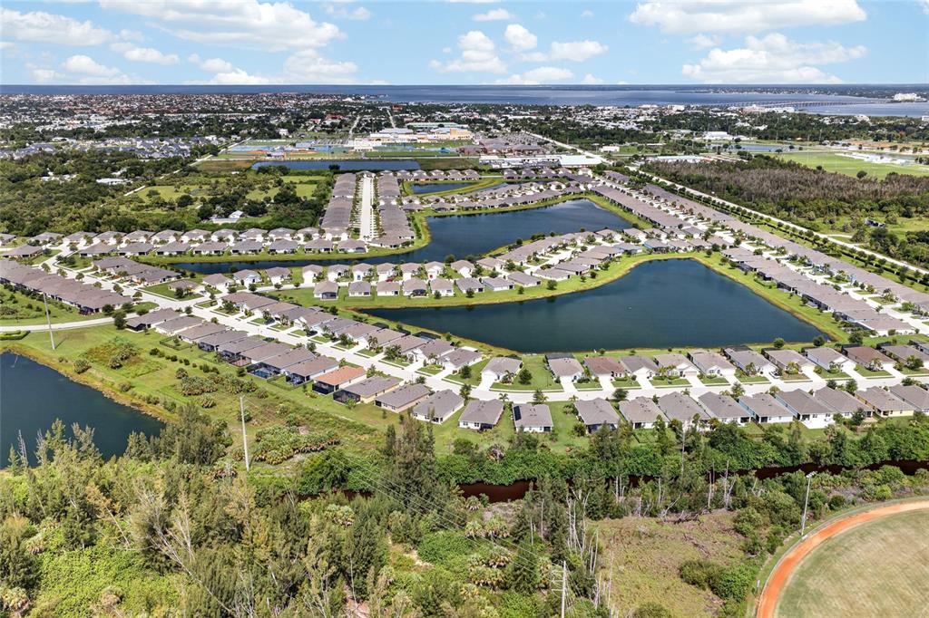 An aerial view shows a suburban residential neighborhood featuring houses surrounding several ponds — 25128 E LENOX CIRCLE, PUNTA GORDA, FL