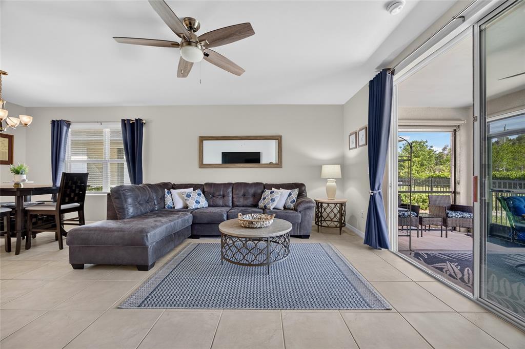 A living room features a gray sectional sofa, a round coffee table, and sliding glass doors — 25128 E LENOX CIRCLE, PUNTA GORDA, FL
