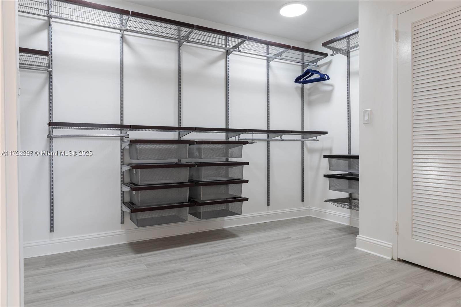 A walk-in closet features wire shelving, pull-out metal baskets, and light wood-look flooring — 5161 Collins Ave # 812, Miami Beach FL 33140, MIAMI BEACH, FL