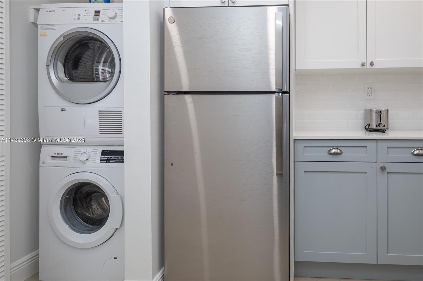 A kitchen area features a stacked washer and dryer next to a stainless steel refrigerator — 5161 Collins Ave # 812, Miami Beach FL 33140, MIAMI BEACH, FL