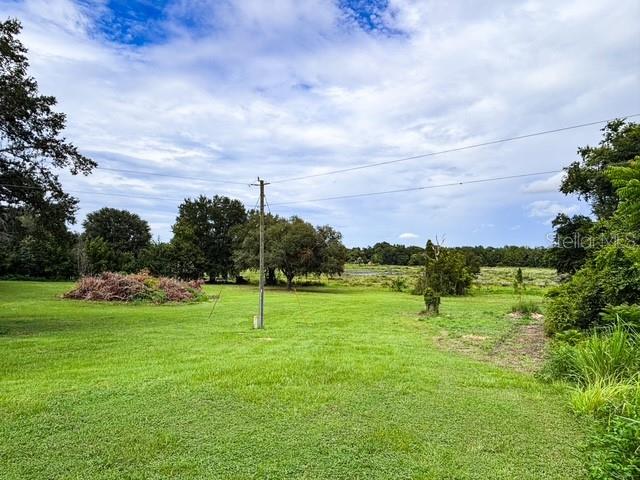 A large, grassy field features a utility pole and a pile of brush under a cloudy sky — 11300 VALLEY VIEW DRIVE, HOWEY IN THE HILLS, FL