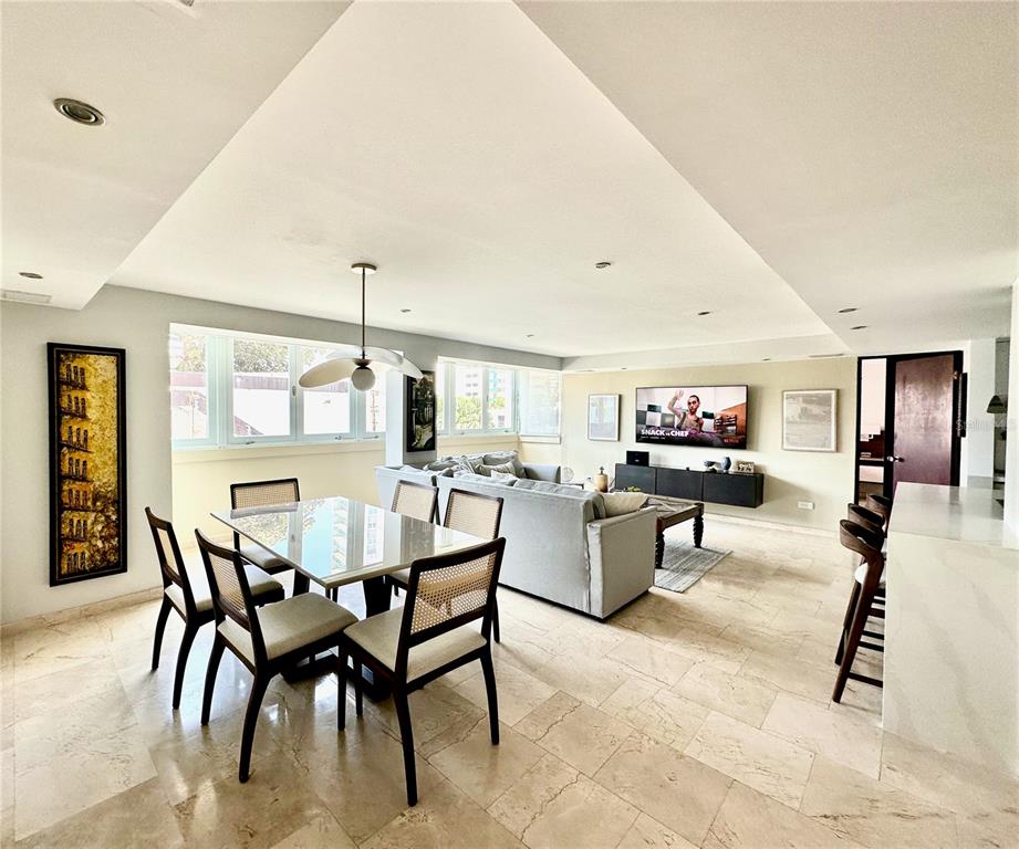 An open-concept living and dining area features tile flooring, a glass dining table, and neutral furniture — 60 Caribe COND. CASTILLO UNIT 3B, SAN JUAN, PR