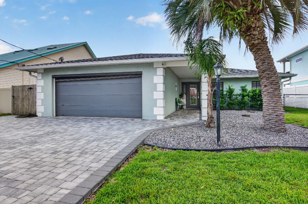 A single-story house with a gray garage door, paved driveway, and a palm tree — 110 CIMMARON DRIVE, PALM COAST, FL