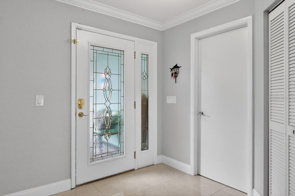 A bright entryway features a white front door with decorative glass, tile flooring, and walls — 110 CIMMARON DRIVE, PALM COAST, FL