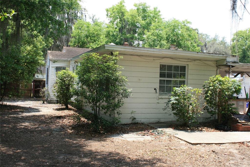 A white, single-story house with horizontal siding and a flat roof sits on a dirt lot — 1822 NW 6TH AVENUE, GAINESVILLE, FL