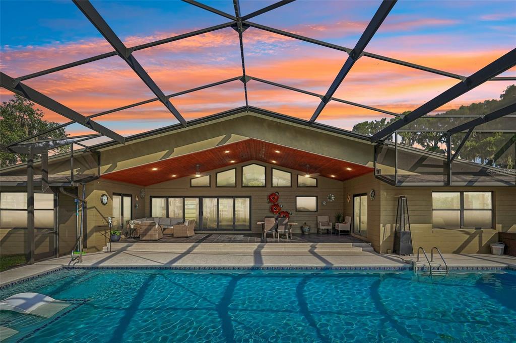 A swimming pool sits in front of a covered patio with a vaulted wood ceiling — 1616 LOVES POINT DRIVE, LEESBURG, FL