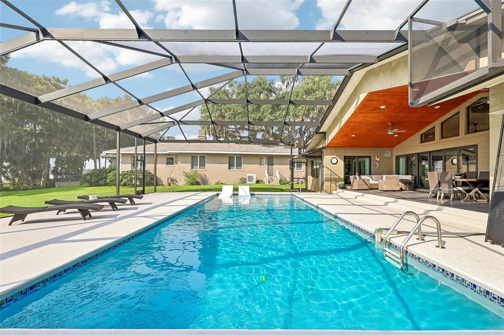A rectangular swimming pool with a screened enclosure and a covered patio area — 1616 LOVES POINT DRIVE, LEESBURG, FL