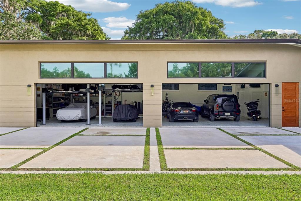 A modern detached garage with two open bays, a concrete driveway, and transom windows — 1616 LOVES POINT DRIVE, LEESBURG, FL