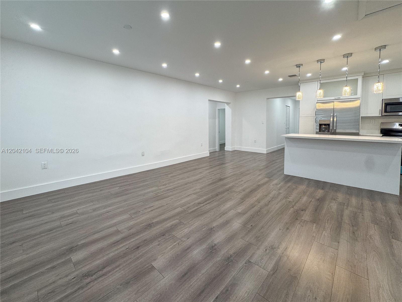 An open-concept living area features white walls, recessed lighting, and wood-look flooring — 1319 NW 40th St, Miami FL 33142, MIAMI, FL