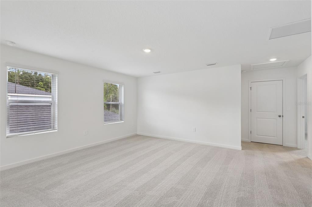 A spacious room with white walls, gray carpet, two windows, and a white door — 108 WANDERING CREEK WAY, PALM COAST, FL