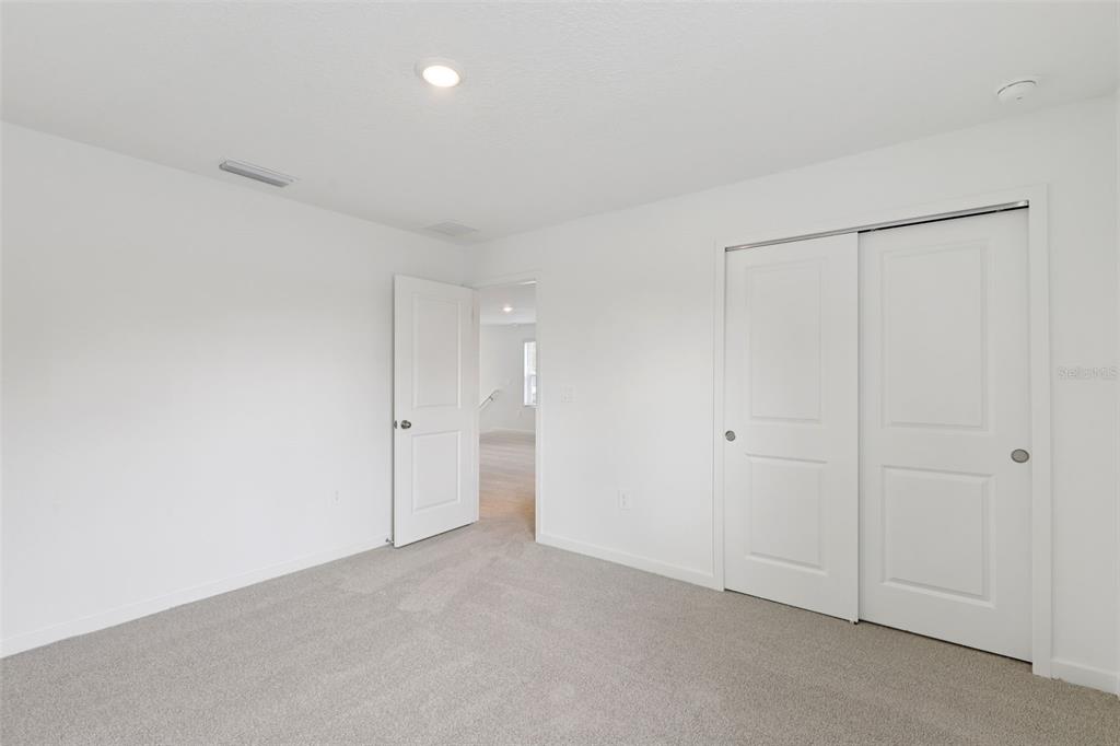 A bedroom with white walls, gray carpet, a closet with sliding doors, and an open doorway — 108 WANDERING CREEK WAY, PALM COAST, FL