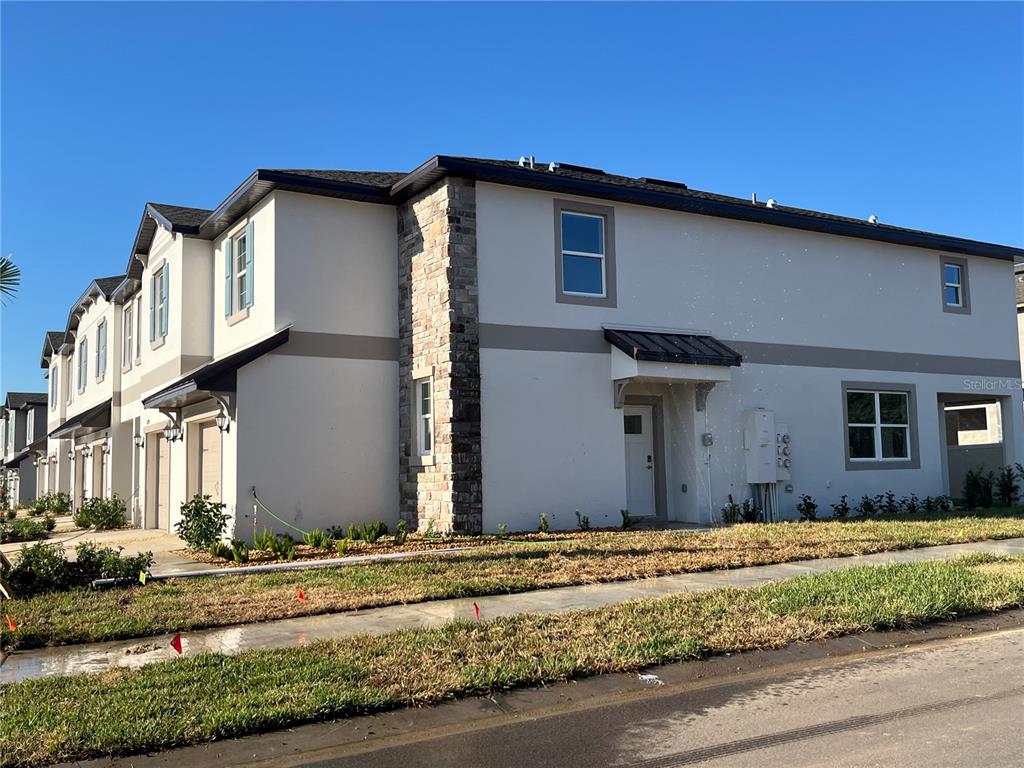 A multi-unit residential building with light-colored stucco walls and stone accents on the exterior — 10288 HONEY HAMMOCK WAY, SAN ANTONIO, FL