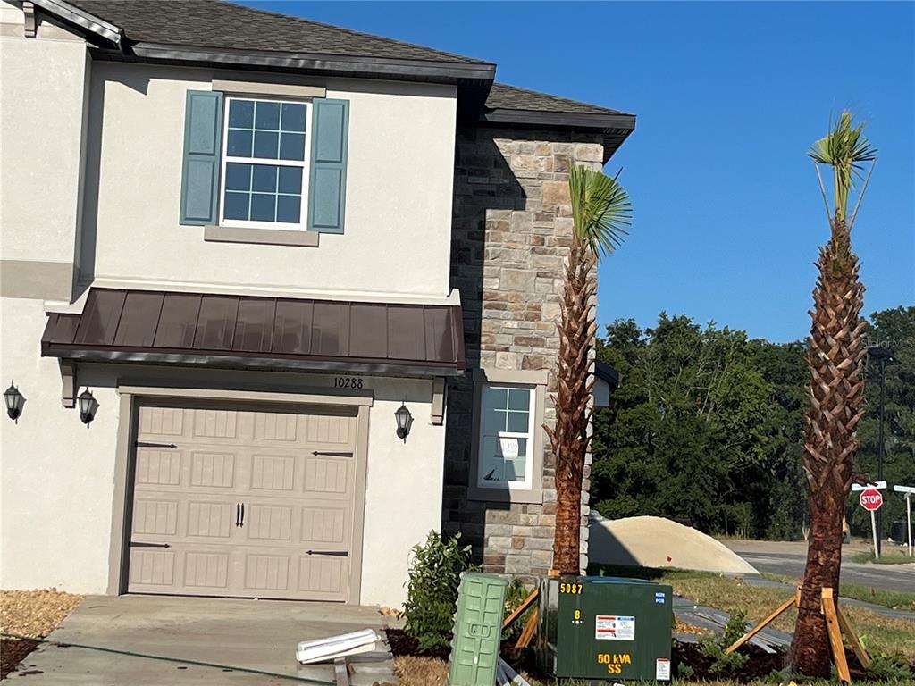 A two-story house exterior features a garage, stone accents, blue shutters, and two palm trees — 10288 HONEY HAMMOCK WAY, SAN ANTONIO, FL