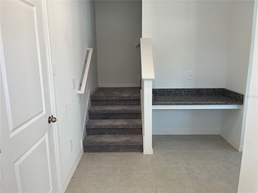 An indoor view shows a carpeted staircase next to a built-in granite desk area — 10288 HONEY HAMMOCK WAY, SAN ANTONIO, FL