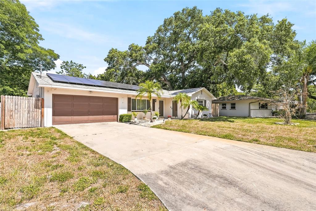 A single-story house with a brown garage door, solar panels, and a concrete driveway — 1318 S HILLCREST AVENUE, CLEARWATER, FL