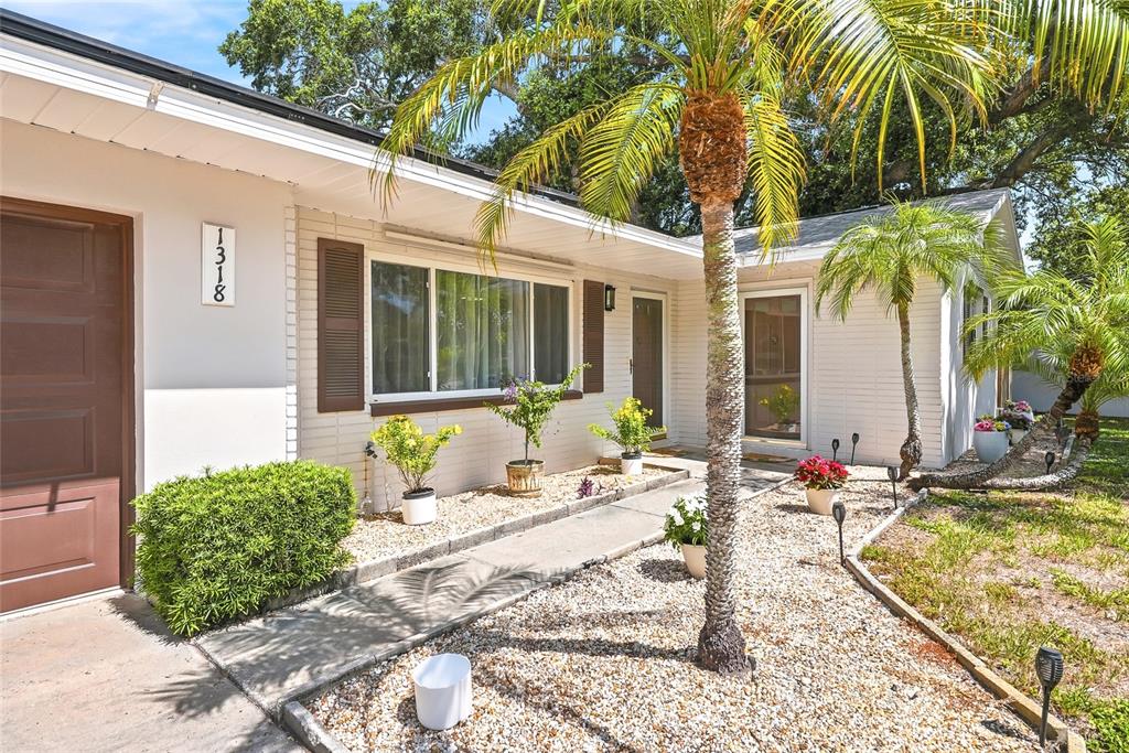 A single-story house with a white exterior, brown shutters, and a gravel front yard — 1318 S HILLCREST AVENUE, CLEARWATER, FL