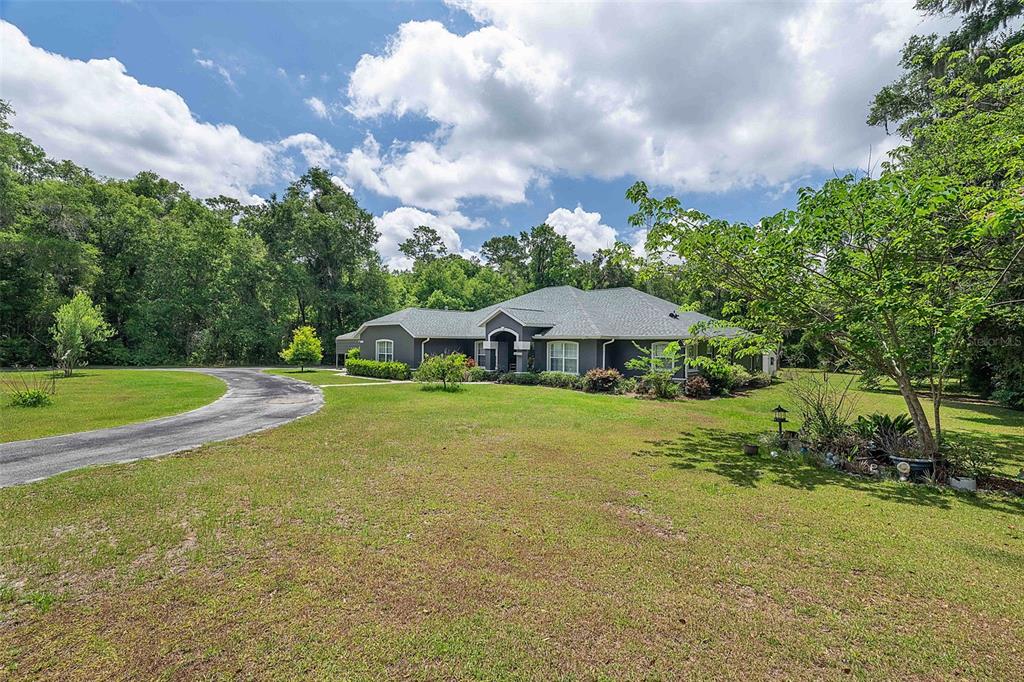 A single-story gray house with a curved driveway sits on a large, grassy lot — 50 NE 35TH STREET, OCALA, FL