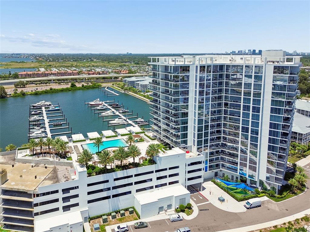 An aerial view shows a modern high-rise apartment building next to a marina and pool — 5120 MARINA WAY UNIT 11003, TAMPA, FL