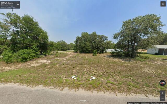 A vacant, grassy lot with scattered trees and sandy patches viewed from a paved road — 000 Maple Course, FL 34488, FL