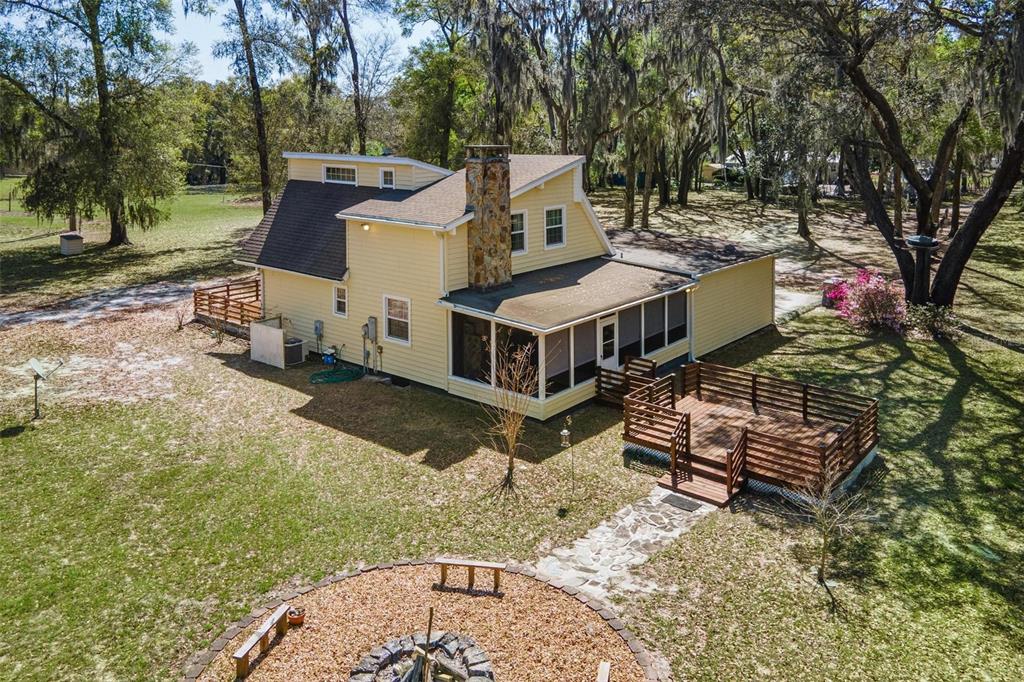 An aerial view of a yellow two-story house with a stone chimney and wooden deck — 2917 LAKE GRIFFIN ROAD, LADY LAKE, FL