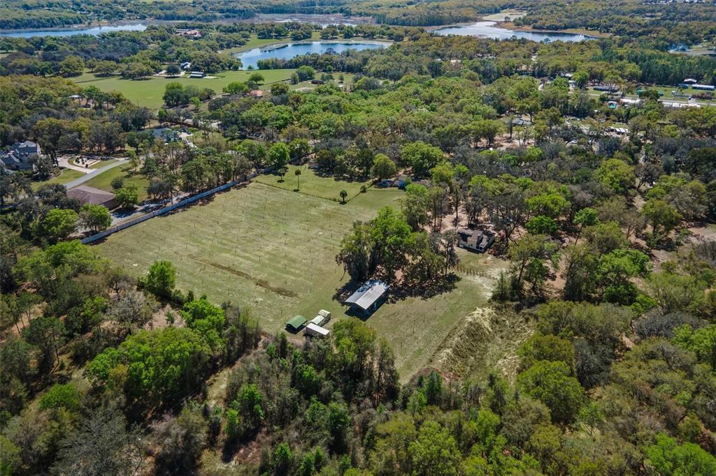 An aerial view shows a large grassy lot with a house, outbuildings, and surrounding trees — 2917 LAKE GRIFFIN ROAD, LADY LAKE, FL