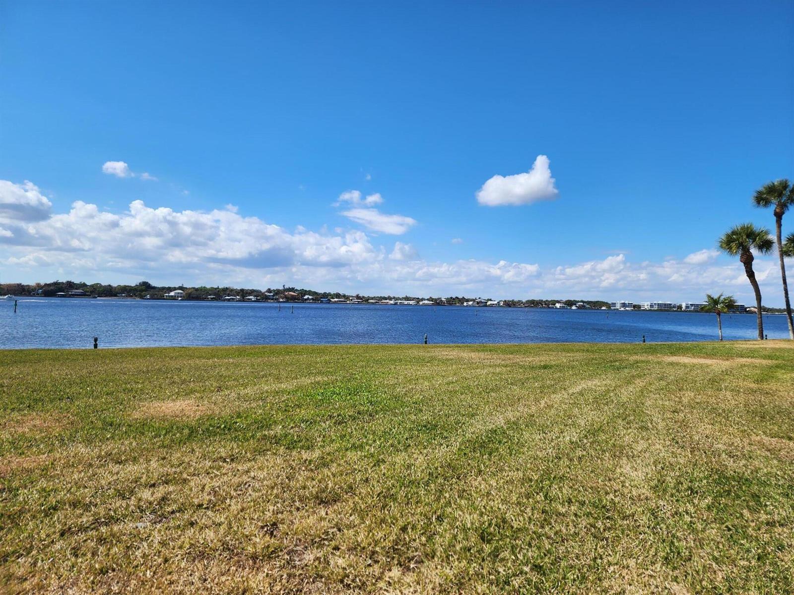 A grassy lawn overlooks a wide body of water with palm trees on the right — 1950 SW Palm City Road # 102, Stuart FL 34994, STUART, FL
