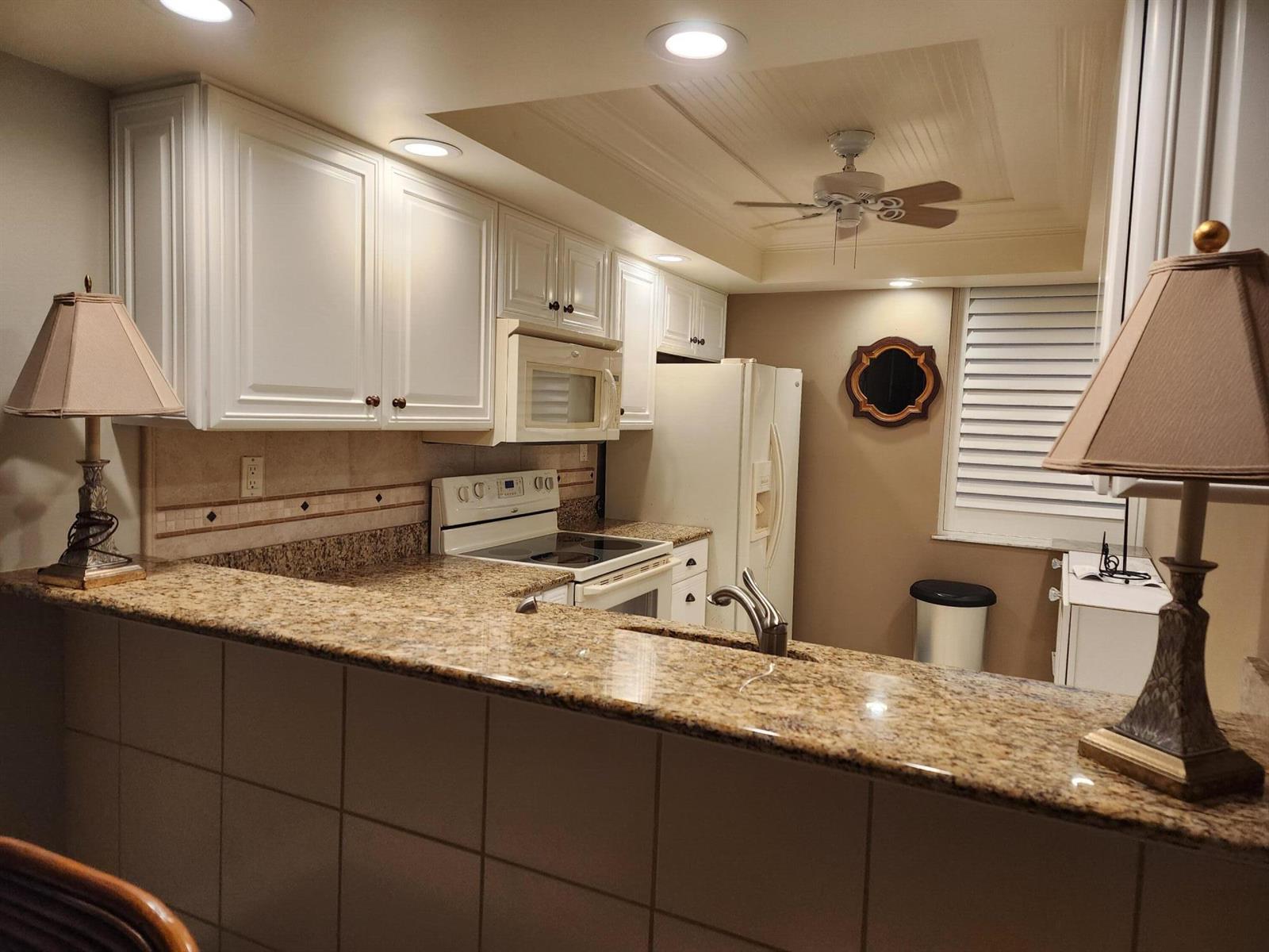 A kitchen features white cabinets, granite countertops, a breakfast bar, and a ceiling fan — 1950 SW Palm City Road # 102, Stuart FL 34994, STUART, FL