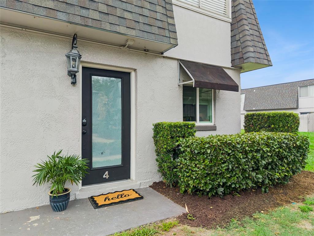 The exterior of a residential unit features a black front door, a small awning, and landscaping — 1922 CONWAY ROAD UNIT 4, ORLANDO, FL