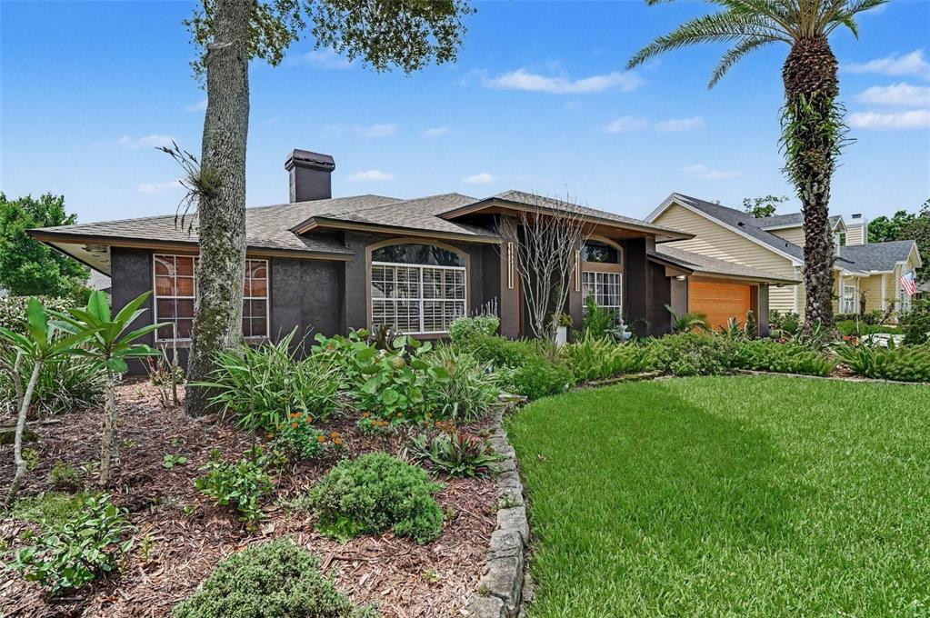 A dark-colored single-story house with a stone-edged garden bed and a palm tree — 455 LONGMEADOW LANE, LONGWOOD, FL