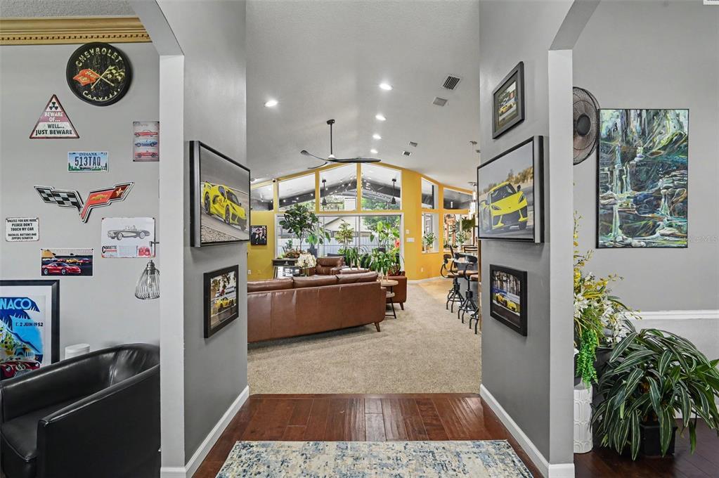 A view through a hallway into a living room with vaulted ceilings and yellow walls — 455 LONGMEADOW LANE, LONGWOOD, FL