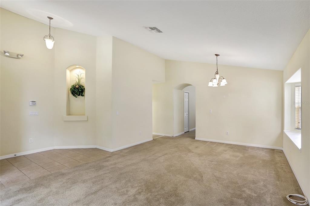 A living room with beige carpet, tile flooring, a recessed wall niche, and two light fixtures — 1029 ORANGE COSMOS BOULEVARD, DAVENPORT, FL