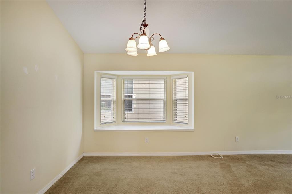 A carpeted room features a bay window with blinds and a hanging chandelier — 1029 ORANGE COSMOS BOULEVARD, DAVENPORT, FL