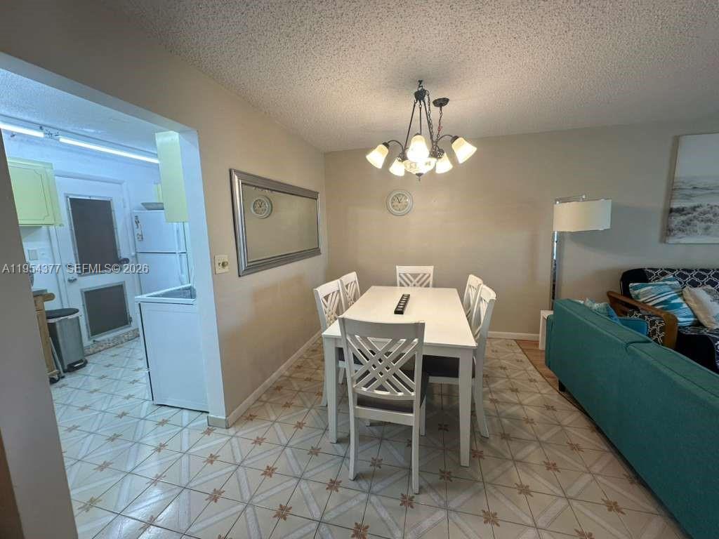 A dining area features a white table, four chairs, a chandelier, and tiled flooring — 17001 NE 13th Ave # 314, Miami FL 33162, MIAMI, FL