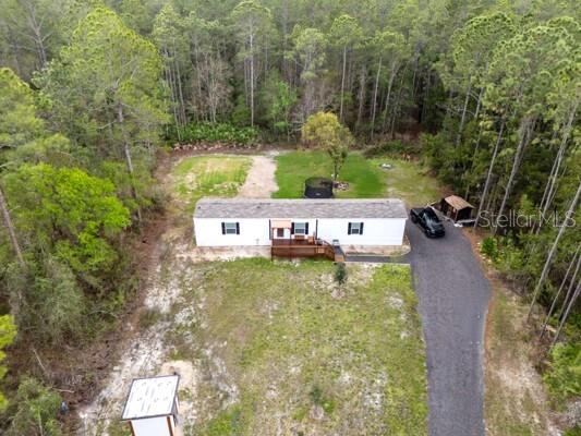 An aerial view shows a white mobile home with a deck on a wooded lot — 5631 IRONWOOD AVENUE, BUNNELL, FL