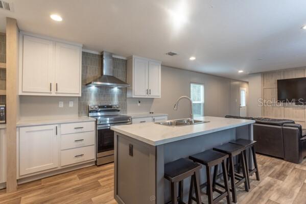 A modern kitchen features white cabinetry, a gray island with bar stools, and stainless appliances — 5631 IRONWOOD AVENUE, BUNNELL, FL