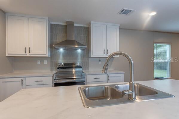 A kitchen featuring white cabinets, a stainless steel range hood, and a central island sink — 5631 IRONWOOD AVENUE, BUNNELL, FL