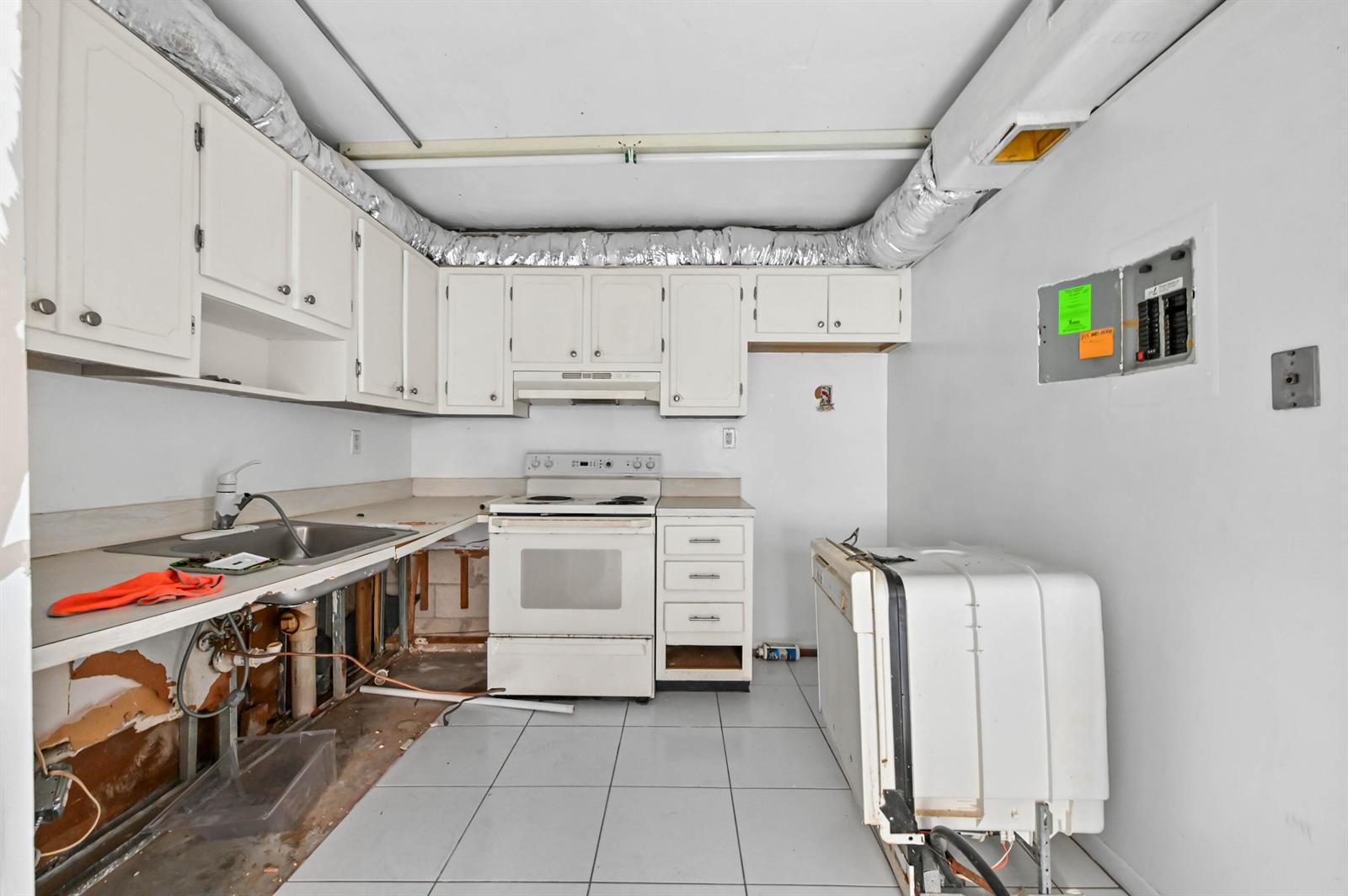 An unfinished kitchen features white cabinets, a stove, a sink, and exposed plumbing — 343 Capri # H, Delray Beach FL 33484, DELRAY BEACH, FL