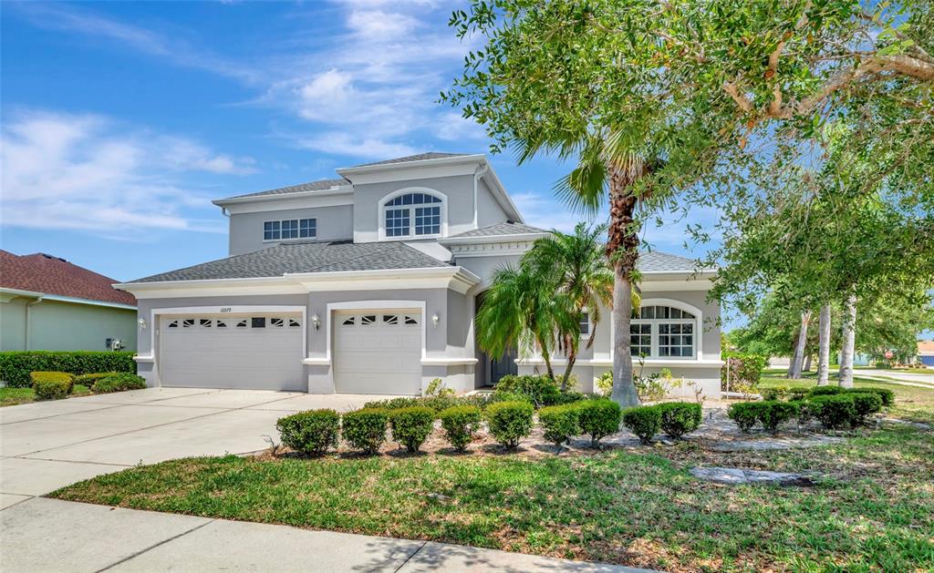 A two-story gray house with a three-car garage and a manicured front lawn — 12079 ASTER AVENUE, BRADENTON, FL