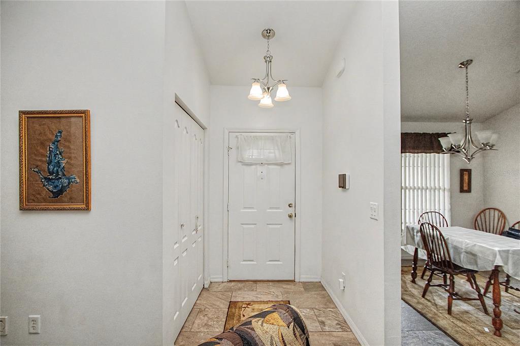 An entryway with tile flooring, a white front door, and a dining area visible nearby — 10908 SW 53RD CIRCLE, OCALA, FL