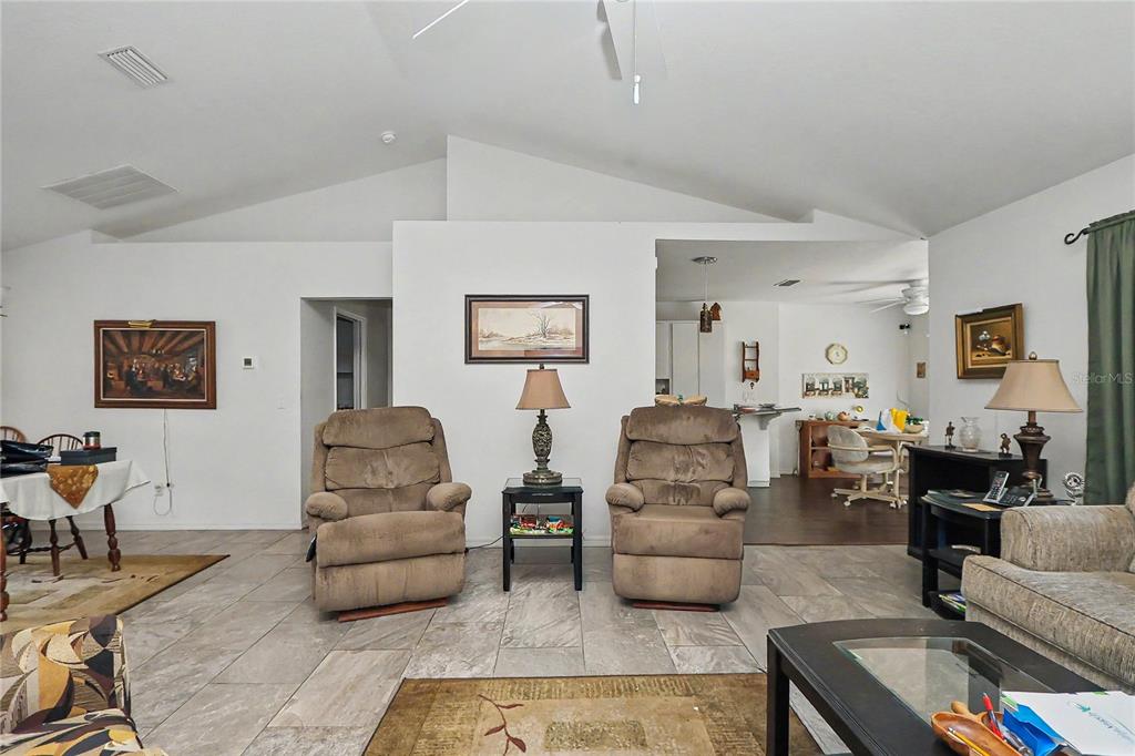 A living room features tiled floors, vaulted ceilings, and two brown recliners with a lamp — 10908 SW 53RD CIRCLE, OCALA, FL