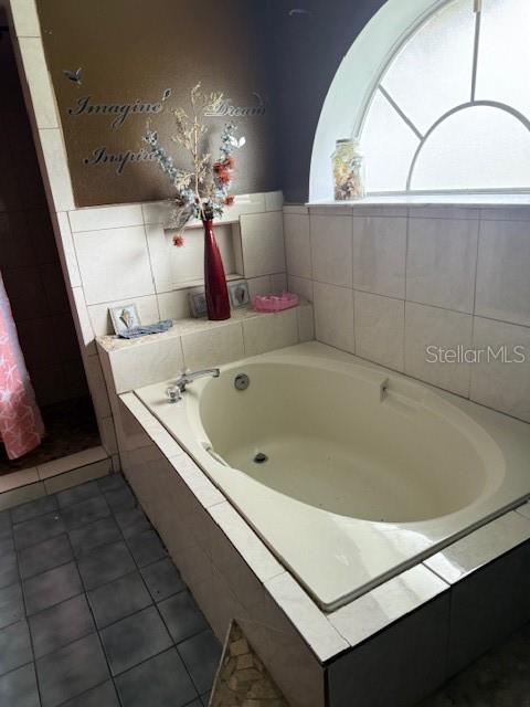 A bathroom features a built-in soaking tub with light-colored tile surround and a large window — 3424 ALISSA COURT, ORLANDO, FL