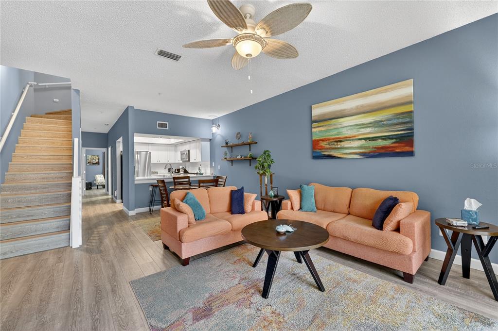 A living room with orange sofas, a coffee table, and stairs leading to an upper level — 320 ISLAND WAY UNIT 603, CLEARWATER, FL